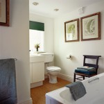 Two frames above a chair with a water closet at the corner